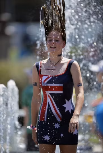 Đợt nắng nóng kinh hoàng đang hoành hành ở Australia dẫn đến cháy rừng và đe dọa tính mạng con người (dễ xảy ra tình trạng say nắng, mất nước..) Trong ảnh, một cô gái tắm mình dưới đài phun nước để hạ nhiệt.