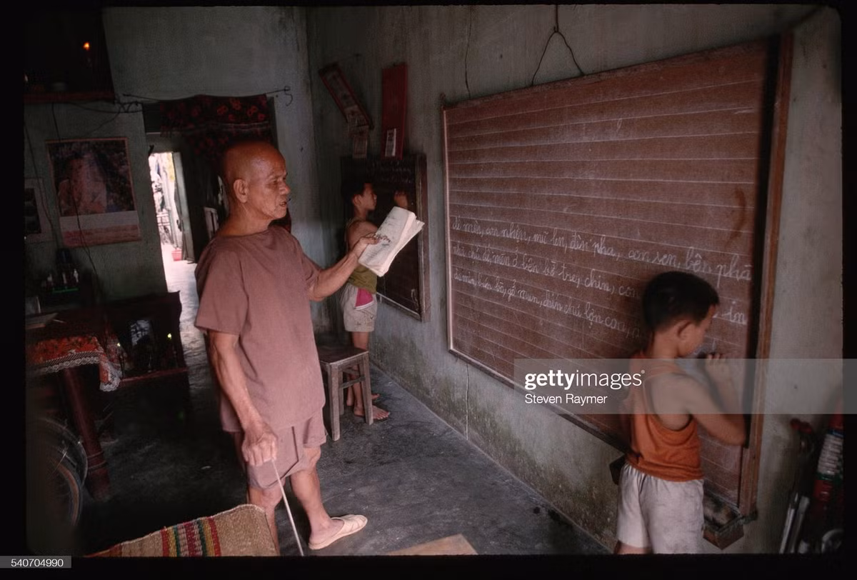 Cụ ông kèm cặp hai đứa cháu nhỏ học hành tại nhà mình ở Hội An, 1993.