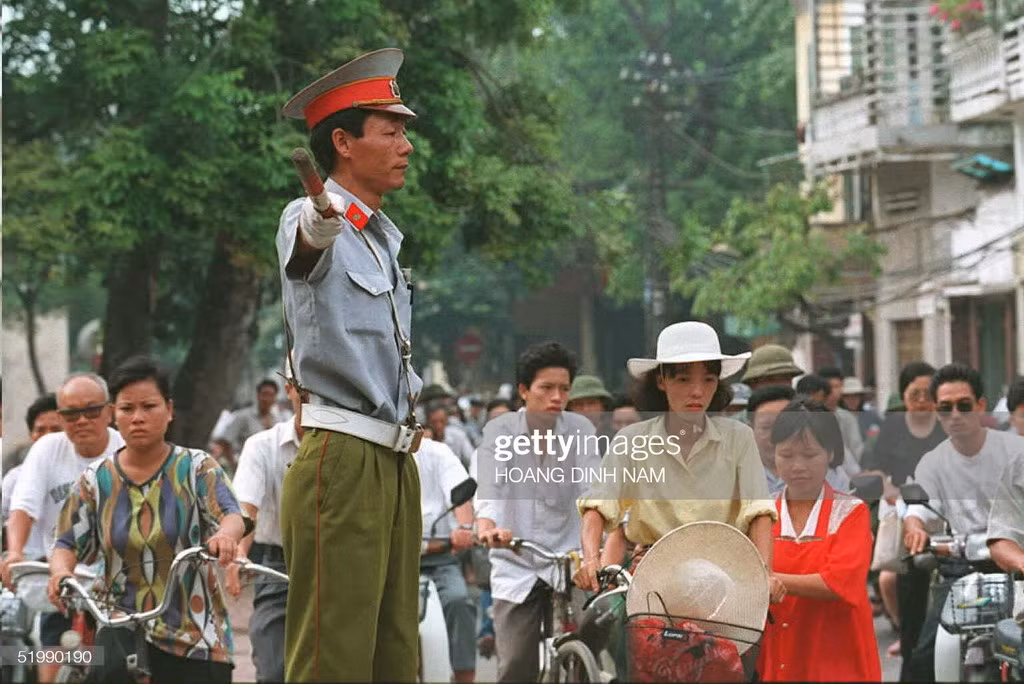 Một cảnh sát giao thông điều khiển phương tiện giao thông trong giờ cao điểm tại góc phố Hàng Gai - Hàng Đào, phố cổ Hà Nội. Ảnh chụp ngày 1/8/1995, ngày mà những mức phạt mới, từ 200.000 đến 50 triệu đồng, được áp dụng cho các hành vi vi phạm luật giao thông.