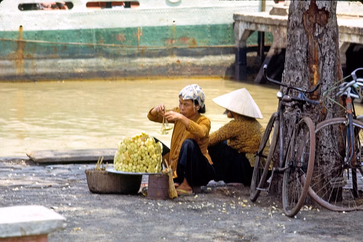 Hai phụ nữ bán mía ghim bên bờ sông Sài Gòn. Theo sự đổi thay của thời cuộc, các quầy mía ghim dần vắng bóng, và ngày nay đã "tuyệt tích" trên đường phố Sài Gòn. Ảnh: Thomas W. Johnson.