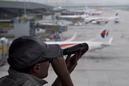 Một người dùng ống nhòm quan sát máy bay tại sân bay quốc tế Kuala Lumpur ngày 18/3.