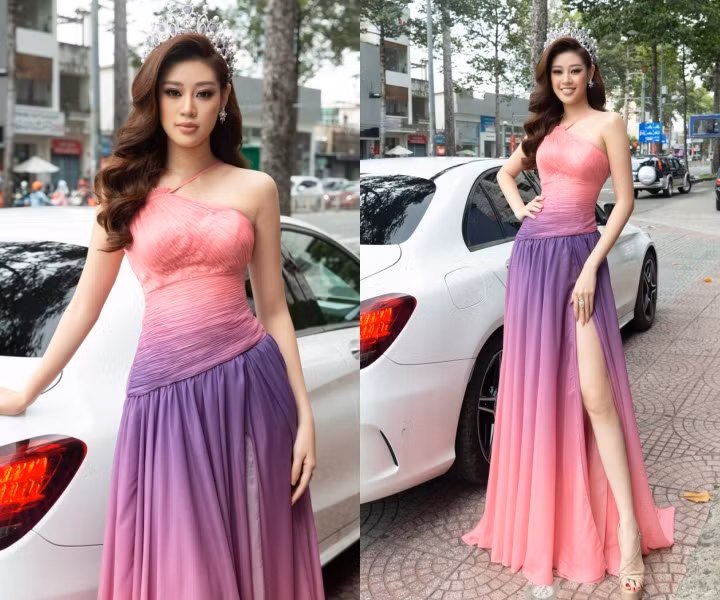 Khánh Vân kiêu kỳ trong thiết kế đầm xếp ly rực rỡ với gam màu tím hồng chủ đạo. Nàng Hậu khéo tôn cặp chân dài thấp thoáng sau đường xẻ tà. Khánh Vân lựa chọn sandals đế cao thanh thoát cùng vương miện Brave Heart sang trọng, nổi bật.