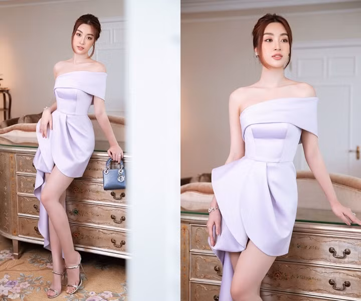 Đỗ Mỹ Linh dịu dàng trong thiết kế đầm cocktail màu tím pastel. Kiểu dáng vai trễ yêu kiều được tô điểm với tùng váy được xếp khối bắt mắt. Chi tiết nhún bèo bất đối xứng vừa mang sắc thái nữ tính lại là nút thắt ấn tượng với người nhìn. Nàng Hậu kết hợp cùng túi xách từ màu xanh lam từ thương hiệu Dior.