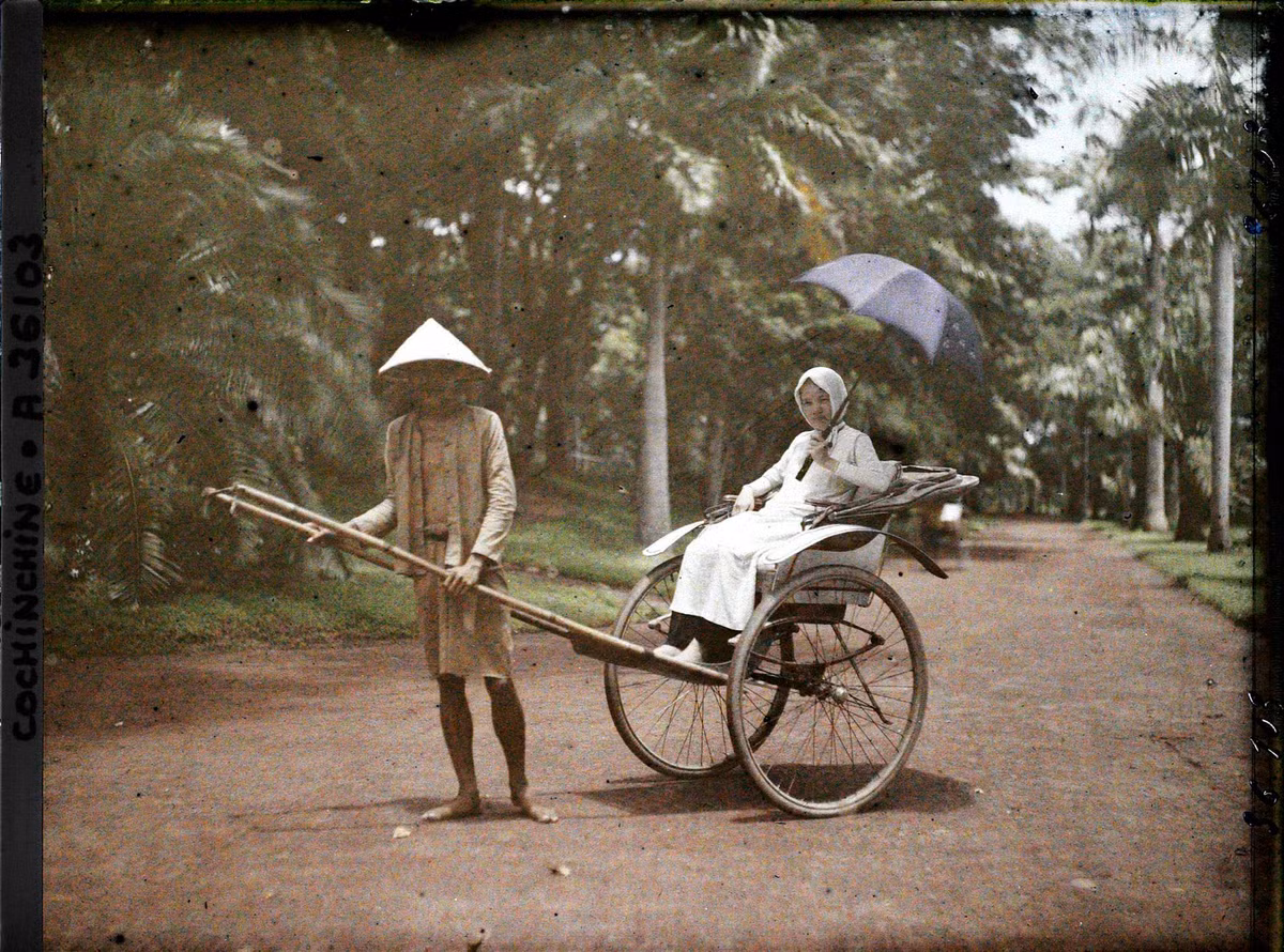 Người phụ nữ trẻ cầm ô, ngồi trên xe tay ở Thảo Cầm Viên Sài Gòn năm 1921.