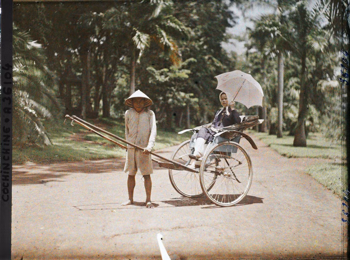 Người phụ nữ trẻ cầm ô, ngồi trên xe tay ở Thảo Cầm Viên Sài Gòn năm 1921.
