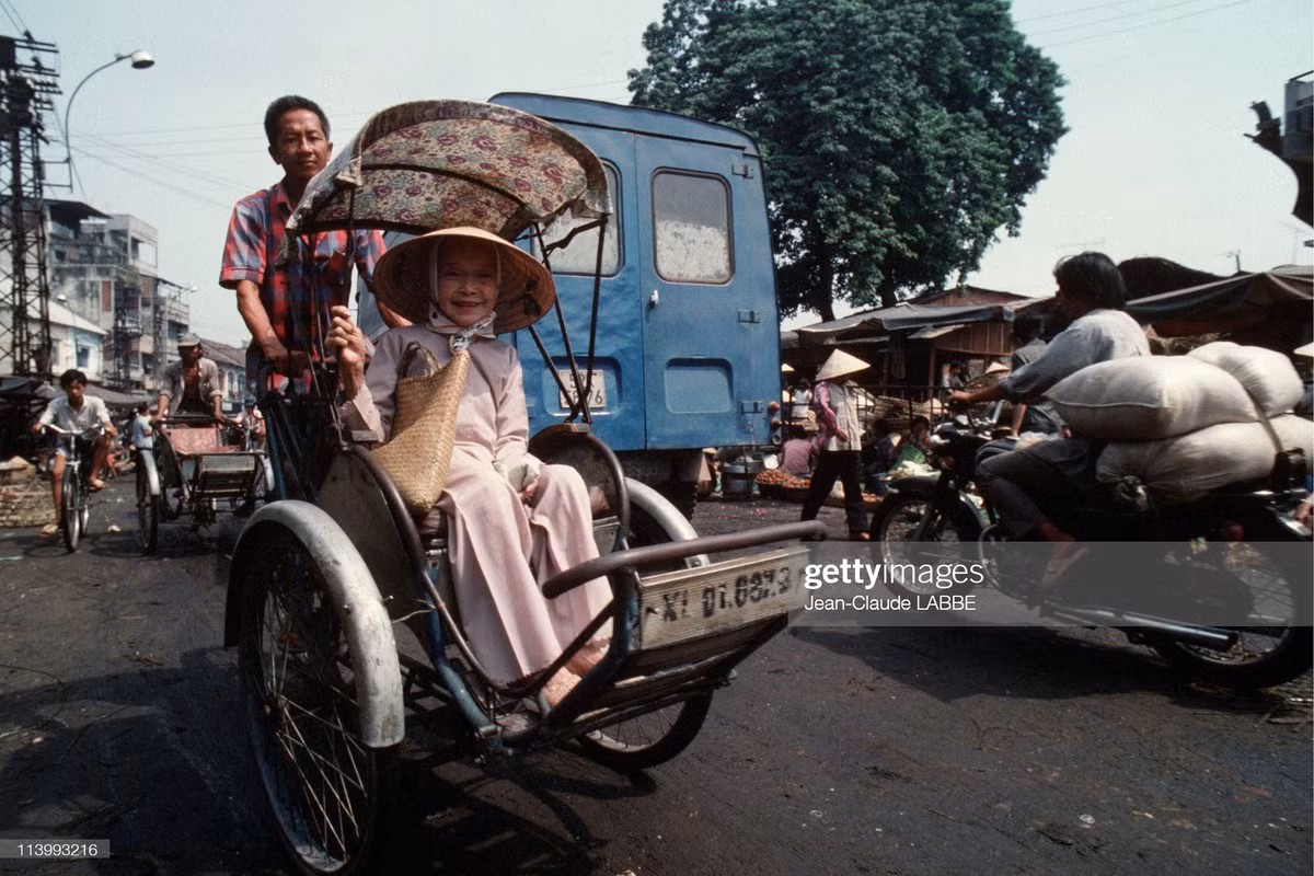 Cụ bà ngồi trên xích lô đi qua một khu chợ ở Sài Gòn vào ngày Giáng sinh năm 1994.