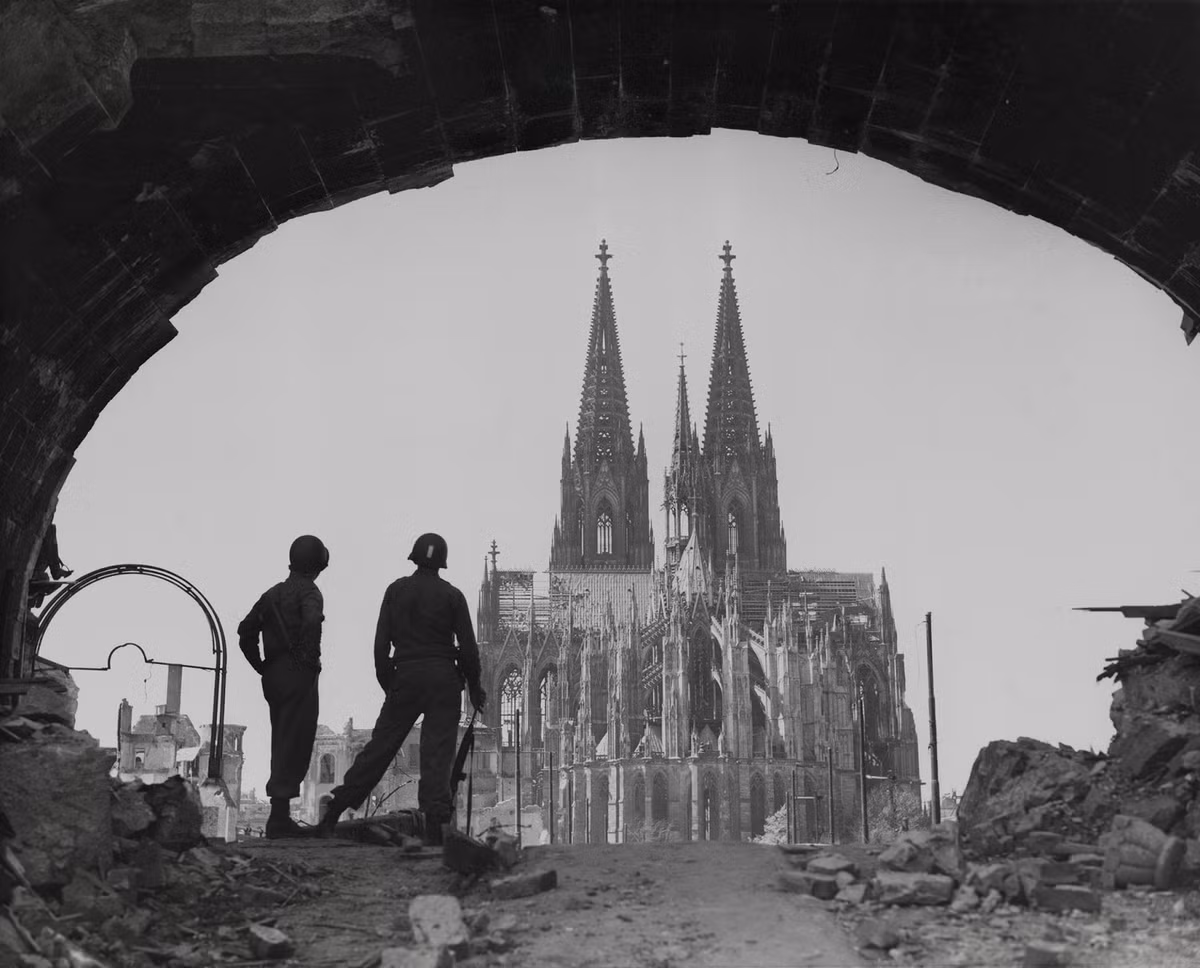 Hai binh sĩ Mỹ đứng giữa đống đổ nát xung quanh Nhà thờ Cologne, thành phố Cologne, nước Đức năm 1945, khi Thế chiến II đã đi đến hồi kết.