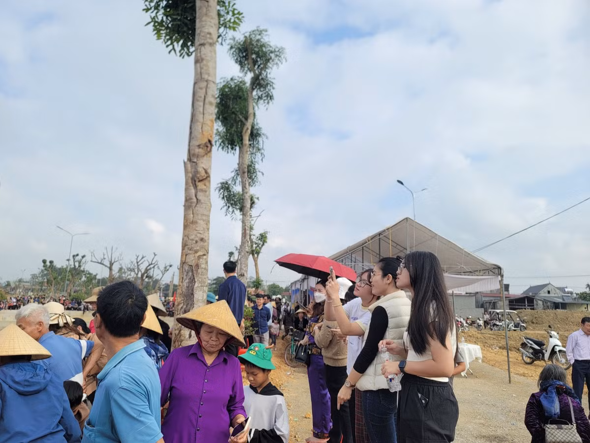 Nhiều bạn trẻ đứng trên bờ quay phim, chụp ảnh lễ hội bắt cá hồ Cầu Bè.