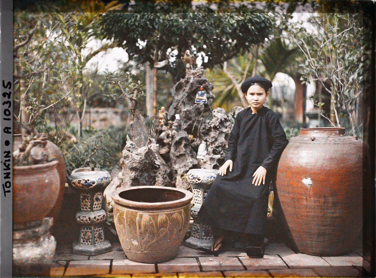 Tiểu thư con nhà giàu ngồi vườn nhà, trước hòn non bộ, Bắc Bộ khoảng năm 1914-1918.