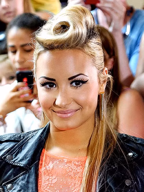 Demi Lovato chọn tóc búi cuốn retro lạ lẫm. Để tạo được kiểu tóc này, các chuyên gia làm đẹp cần tới máy làm xoăn tay, lược chải chuyên dụng, ghim kẹp tóc và thật nhiều gôm giữ nếp.