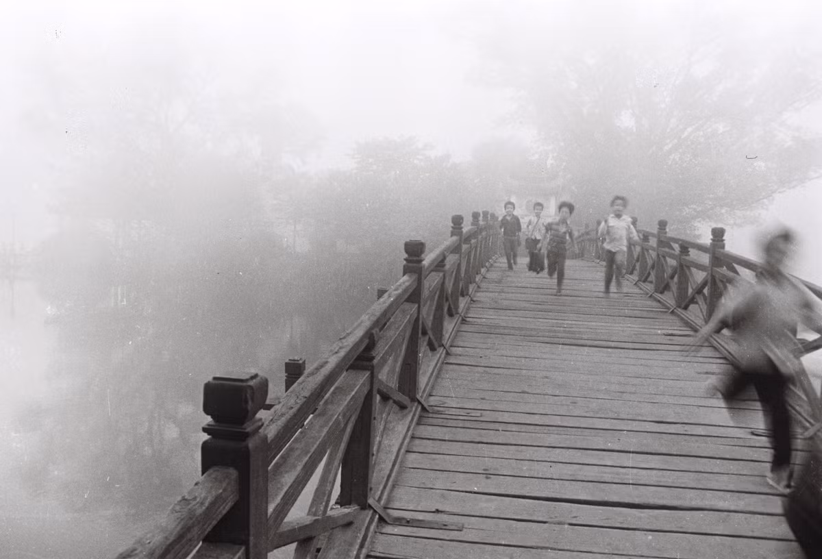 Những đứa trẻ nô đùa trên cầu Thê Húc dẫn vào đền Ngọc Sơn. Khi đó, cây cầu này màu đỏ son, làm bằng gỗ và có nhiều trụ liên tiếp.