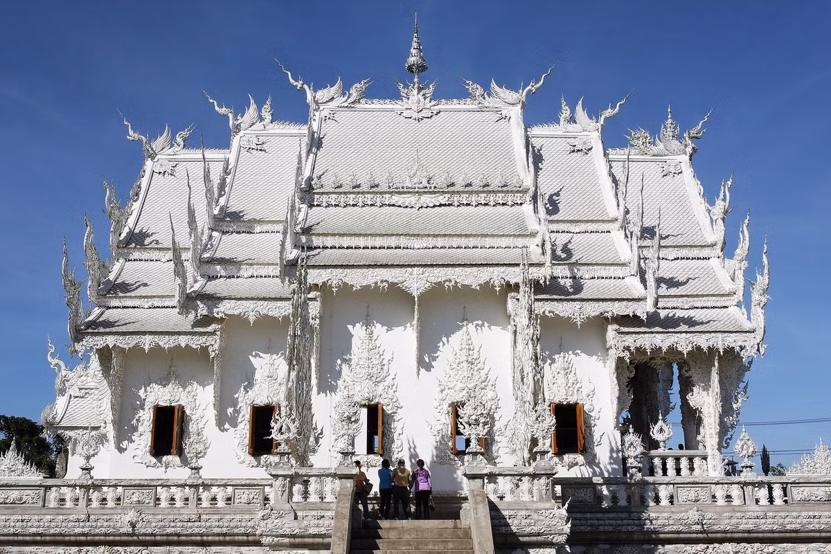 Sau gần 2 thập niên xây dựng, Wat Rong Khun đã hiện ra trong một màu trắng tinh khôi, cùng sự pha trộn kỳ lạ của kiến trúc truyền thống và siêu thực, gây ấn tượng mạnh mẽ đối với những ai đến đây. Ảnh: Wikipedia.