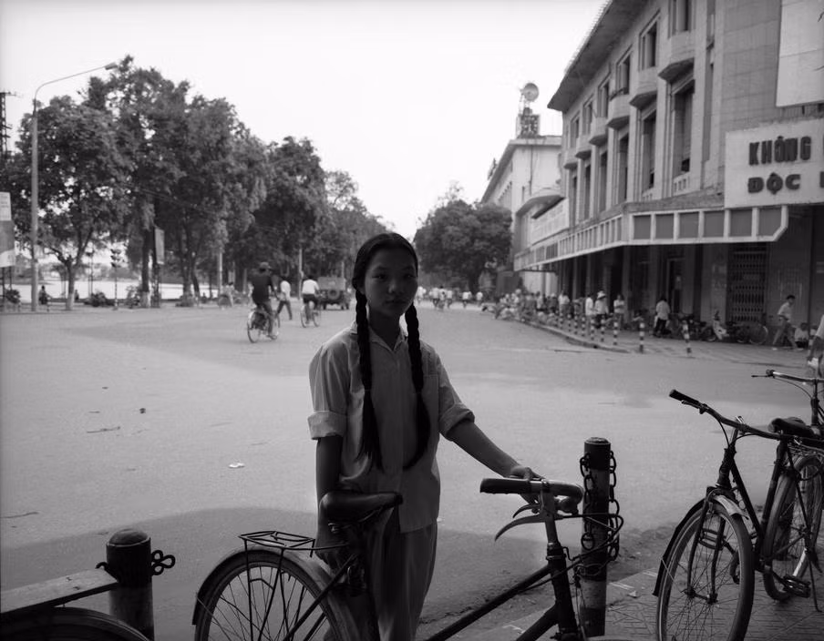 Thiếu nữ và chiếc xe đạp ở vỉa hè bên ngoài bách hóa Tràng Tiền.