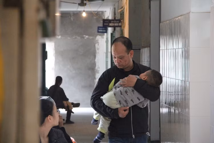 Khuôn mặt buồn bã của một người bố bế con điều trị tại bệnh viện Đa khoa Xanh Pôn (Ba Đình, Hà Nội).