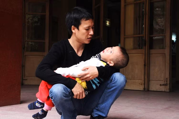 Anh Đàm Đình Giang (Sóc Sơn, Hà Nội) ân cần chăm sóc cậu con trai trong bệnh viện Xanh Pôn, vì cháu bị ngã, gãy cánh tay phải.