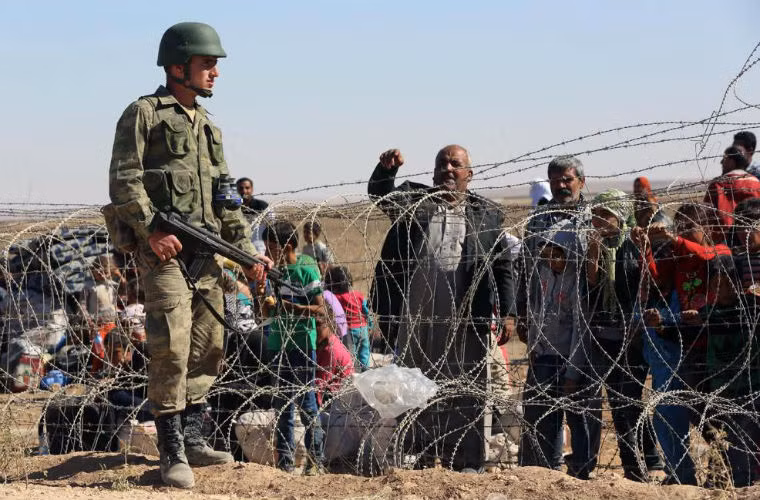 Binh sĩ Thổ Nhĩ Kỳ đi tuần dọc biên giới trong khi hàng trăm người Syria chờ đợi. Binh sĩ Thổ Nhĩ Kỳ đi tuần dọc biên giới trong khi hàng trăm người Syria chờ đợi.