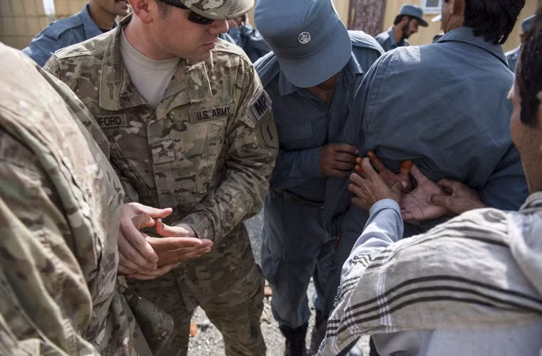 Các binh sĩ Mỹ hướng dẫn cách kiểm soát các nghi phạm cho cảnh sát Afghanistan.