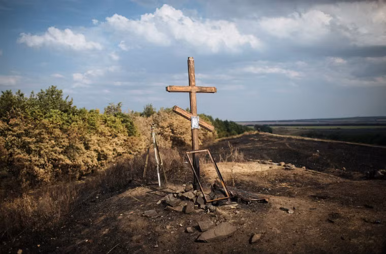 Thánh giá đặt trên cánh đồng bị cháy ở Donetsk.