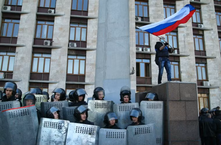 Người biểu tình treo cờ Nga khi tiến vào tòa nhà thị chính Donetsk ngày 6/4/2014. Người biểu tình chiếm được nhiều tòa nhà tại các thành phố miền đông Ukraine khiến Kiev cáo buộc Moscow đang muốn chia cắt Ukraine.
