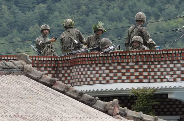 Các binh sĩ Hàn Quốc trên nóc nhà bao vây binh sĩ Yim. Đấu súng đã nổ ra giữa 2 bên.
