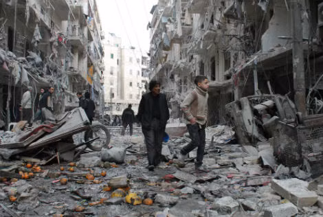 Một người già Syria dẫn đứa trẻ đi dạo trong một khu vực bị tàn phá do bom của trực thăng quân đội chính phủ Syria vào ngày 18/3/2014 ở Aleppo.