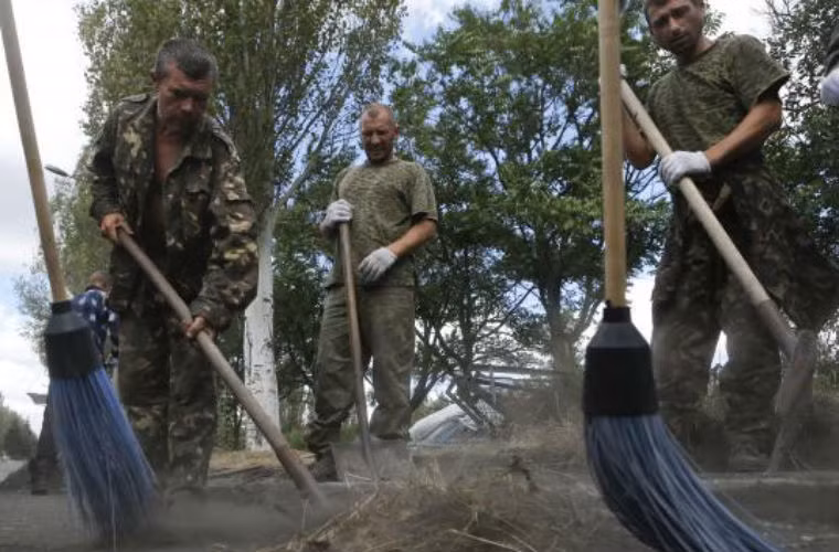 Các binh sĩ Ukraine - bị bắt giữ đang đi quét đường.