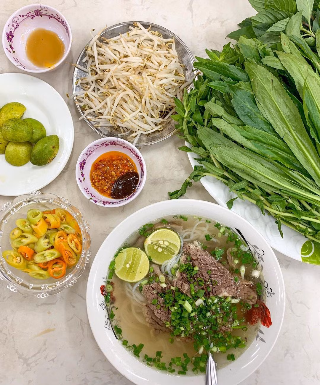 Ngò rí, ngò gai ở miền Nam được gọi mùi ta (rau mùi), mùi tàu ở miền Bắc. Đây đều là những loại gia vị khá quen thuộc trong ẩm thực Việt Nam. Lấy phở bò làm ví dụ. Tại TP.HCM, người ta thường phục vụ phở bò kèm theo đĩa giá sống hoặc giá trụng, chanh, ớt, ngò gai, húng quế... Ảnh: Agirlaboutchicago.