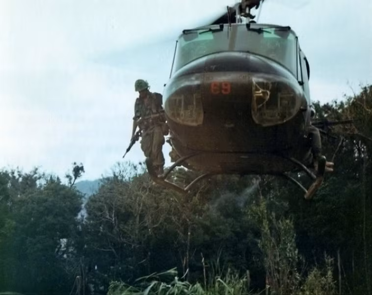 Lính Mỹ đứng trên càng hạ cánh của một chiếc UH-1, quan sát địa hình trước khi đổ bộ. Ảnh: Army.mil.