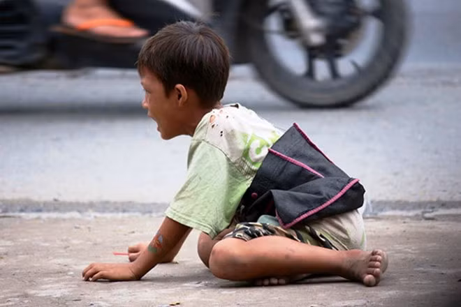 Bà Nguyễn Thị Út - chủ một quán cà phê ở ngã ba này - cho biết: “Những đứa trẻ ăn xin này rất liều, chúng không biết sợ là gì. Cứ thấy xe dừng là chạy ùa ra xin tiền. Nhưng những đứa trẻ này cũng tội nghiệp lắm, xin được bao nhiêu tiền bị người lớn giữ hết. Rồi tụi nó đem đi đánh đề, mua vé số hết”. Trong ảnh: Trẻ ăn xin được dạy “khổ nhục kế” quỳ lạy, khóc van thảm thiết
