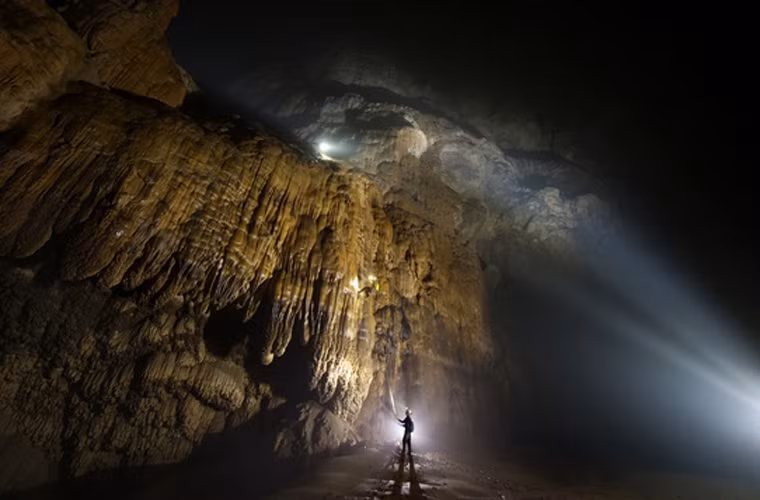 Ở đáy hang, con người chỉ như một dấu chấm nhỏ quanh những khối thạch nhũ to lớn.