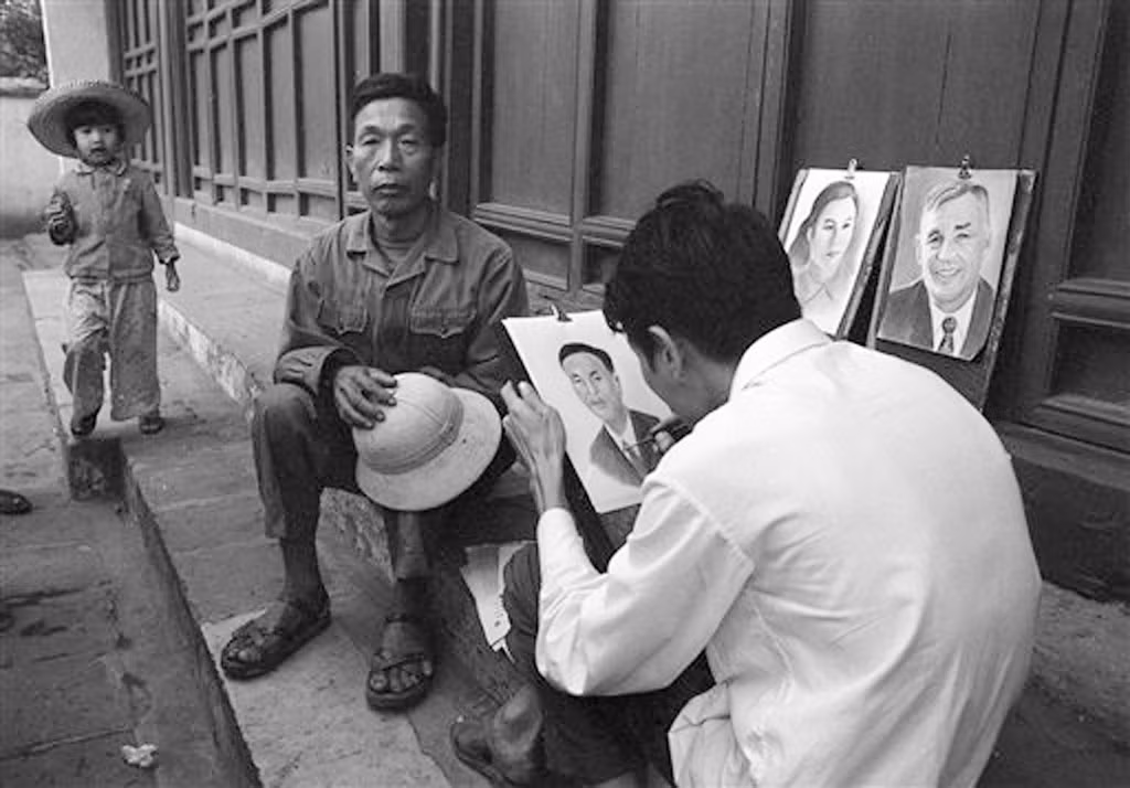 Trước điện thờ của đền Ngọc Sơn, người họa sĩ đường phố vẽ chân dung một người đàn ông, đứa con gái nhỏ đứng chờ cạnh đó, 29/3/1973.