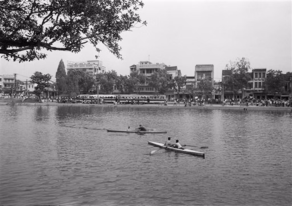 Người dân chèo thuyền thư giãn trên hồ Gươm, Hà Nội ngày 29/3/1973. Hình chụp từ cầu Thê Húc hướng về ga tàu điện bờ hồ. Có thể thấy toa tàu điện ở ga. Ảnh: Horst Faas / AP Photo.