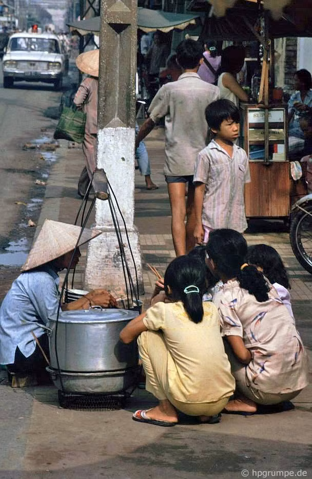 Phụ nữ và trẻ em ngồi xổm ngay trên lòng đường để ăn quà vặt.