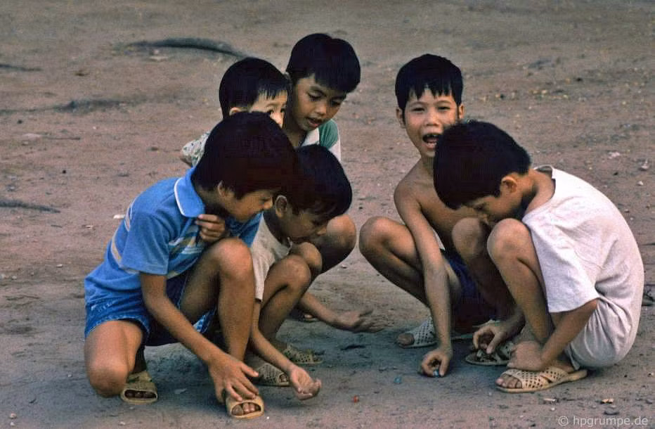 Các cậu bé chơi bắn bi trên một đoạn vỉa hè trải bê tông ở bờ hồ, 1992.