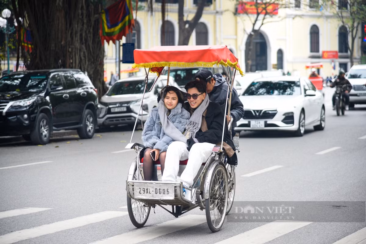 Hai khách du lịch co ro trên xe xích lô khi đi tham quan phố phường Hà Nội.