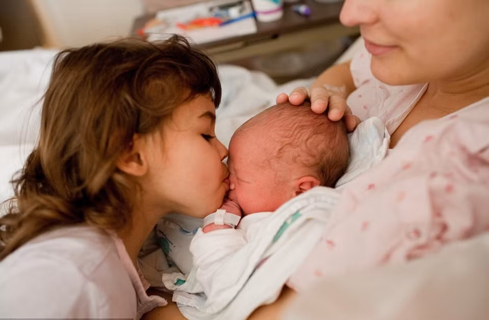 Người chị hôn đứa em bé bỏng âu yếm.