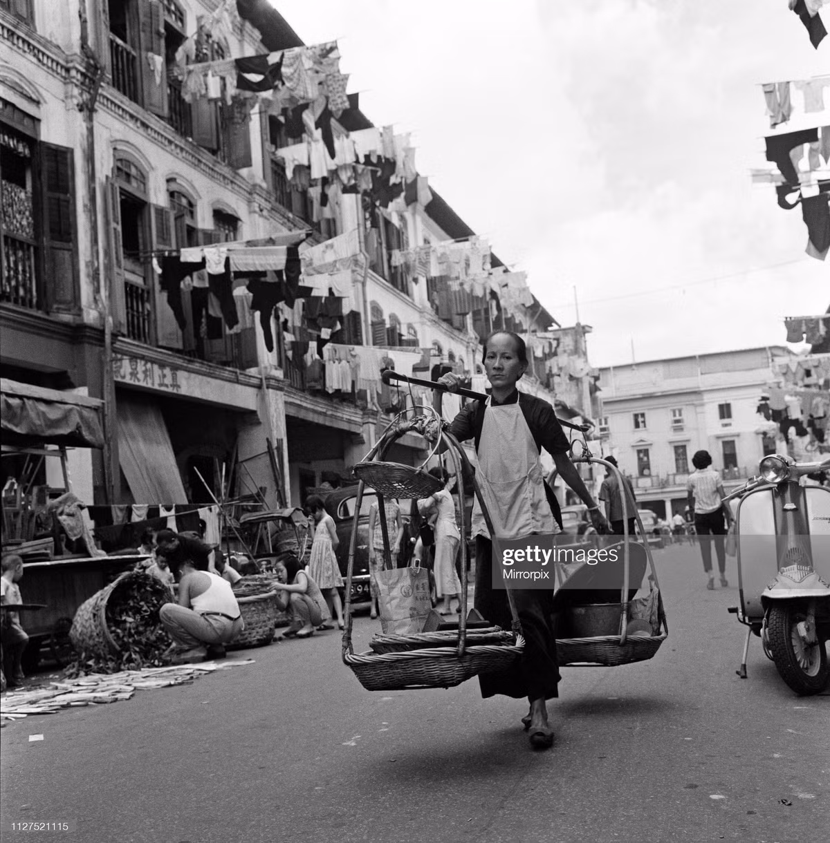 Một người phụ nữ người Hoa với quang gánh trên vai bước đi trong khu phố Tàu Singapore, ngày 6/2/1962.