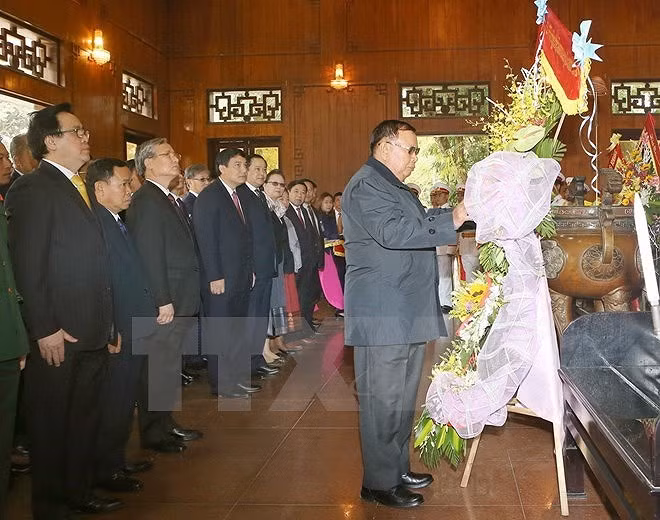 Trước đó, sáng 21/12, Tổng Bí thư, Chủ tịch nước Lào Bounnhang Vorachith và đoàn đại biểu cấp cao của Đảng, Nhà nước Lào đã đến dâng hương, dâng hoa tưởng niệm Chủ tịch Hồ Chí Minh tại Khu Di tích Kim Liên, xã Kim Liên, huyện Nam Đàn, tỉnh Nghệ An; thăm nhà lưu niệm của Chính phủ nước Cộng hòa Dân chủ Nhân dân Lào tặng Khu lưu niệm Chủ tịch Hồ Chí Minh tại Khu Di tích Kim Liên. (Ảnh: TTXVN)