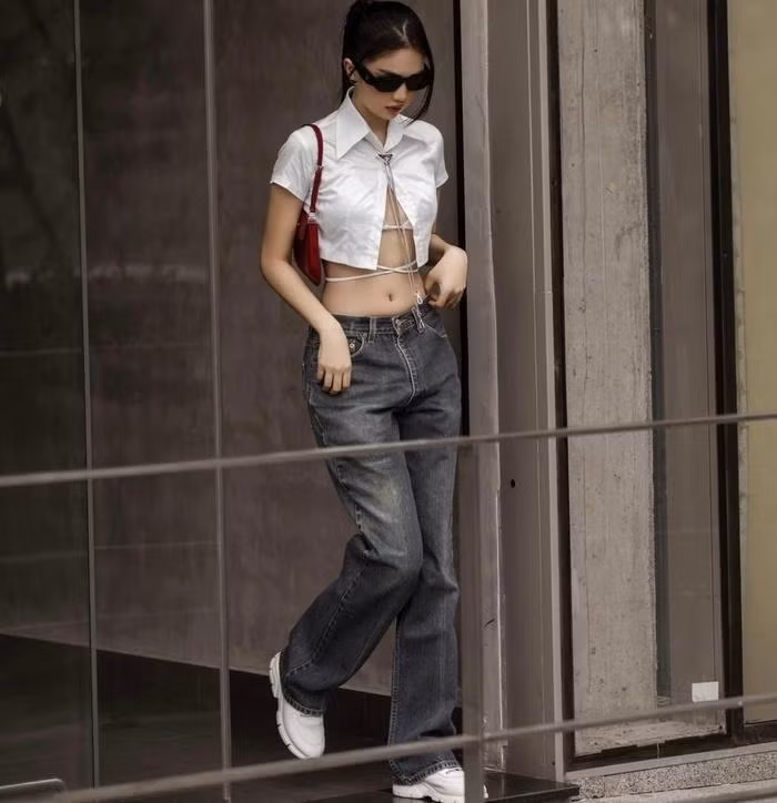 Ngọc Trinh trung thành với style sexy hết nấc áo croptop lộ nội y phối cùng quần jeans ống suông, túi kẹp nách.
