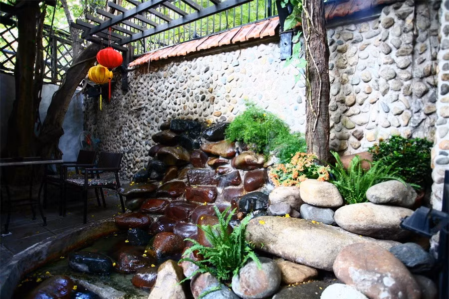 Nằm trên một con phố khá yên tĩnh của quận 1, TP Hồ Chí Minh; café “Thềm xưa” là một khoảng lặng trong lòng phố. Không gian ở đây thoáng đãng và yên bình. Đó là sự kết hợp hài hoà giữa kiến trúc và những khoảng xanh nho nhỏ của sân vườn. Ảnh: Một góc sân vườn với các vật liệu sỏi đá tự nhiên.