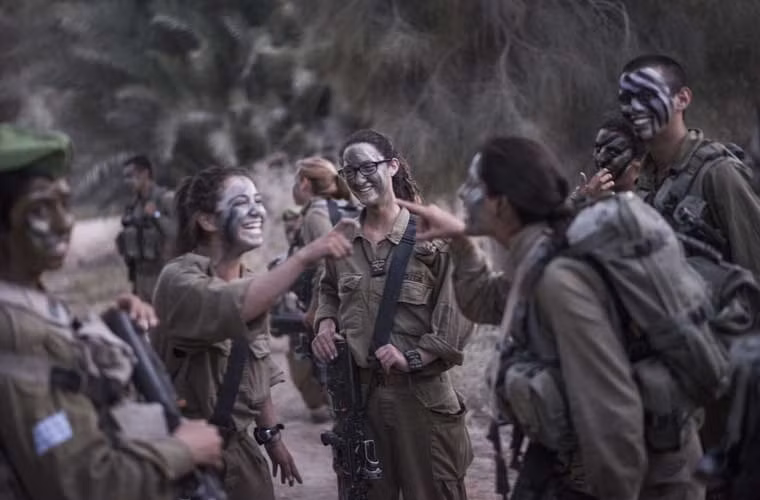 Nữ binh sĩ Israel với “lớp phấn trang điểm quân đội” đang trêu đùa với nhau trước giờ bước vào cuộc tập trận.
