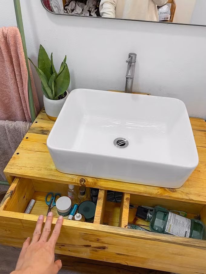 Tủ gỗ bồn rửa mặt có ngăn kéo để đồ cho gọn, một bên đựng đồ chăm sóc da, một bên chứa bàn chải.