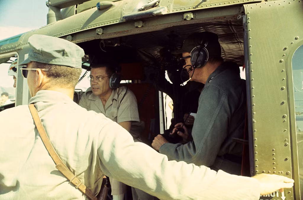 Bộ trưởng Quốc phòng Mỹ Robert McNamara (giữa) ngồi trên một chiếc trực thăng, nói chuyện với hai sĩ quan trong một chuyển khảo sát thực địa tại chiến trường Việt Nam. Ảnh: Jean-Claude Sauer.