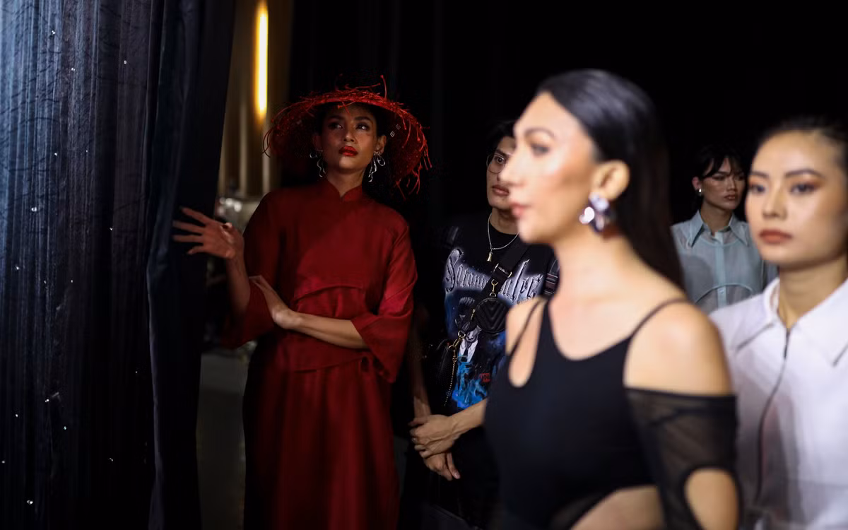 Trước khi ra sân khấu, Võ Hoàng Yến được chỉnh sửa lại lớp make-up, tô son đỏ đậm để ton sur ton với màu sắc trang phục. Là vedette nên siêu mẫu 33 tuổi sẽ bước ra runway cuối cùng, do đó, cô phải đứng nép vào góc cánh gà để nhường không gian cho dàn người mẫu đi trước mình.