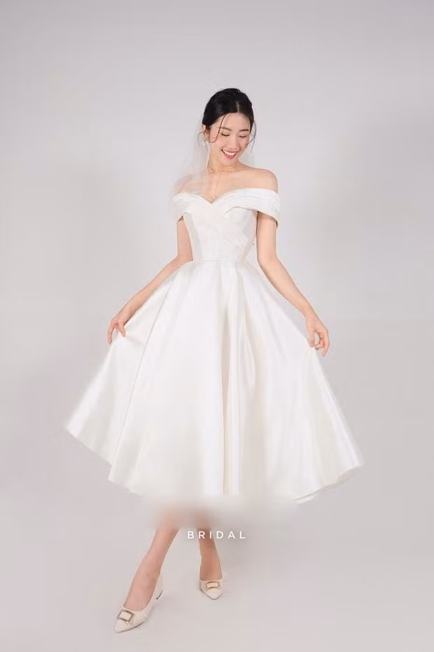 Diễn viên Thúy Ngân không diện đầm hoành tráng mà chỉ mặc váy cưới ngắn, trễ vai khá năng động cùng một đôi giày đơn giản.