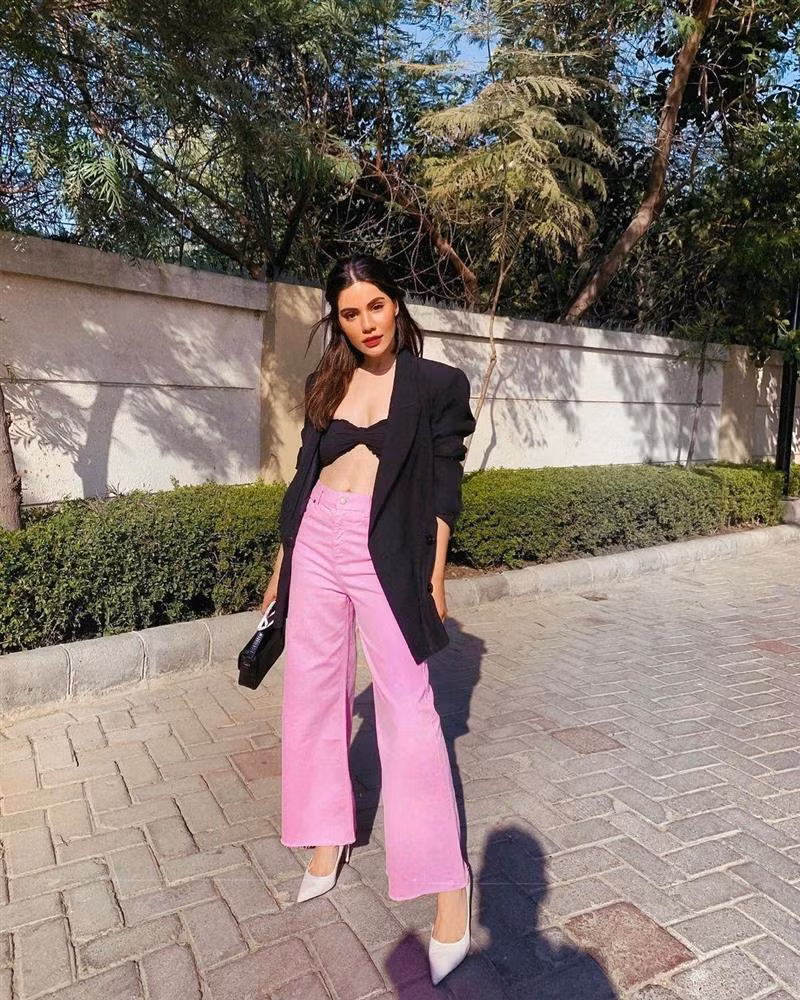 Quần ống loe hồng tím dịu mắt được fashion blogger Roshni Bhatia mix cùng áo ngực, khoác ngoài chiếc blazer ngoại cỡ màu đen. Giày cao gót mũi nhọn màu trắng giúp cân bằng bộ outfit của người đẹp.