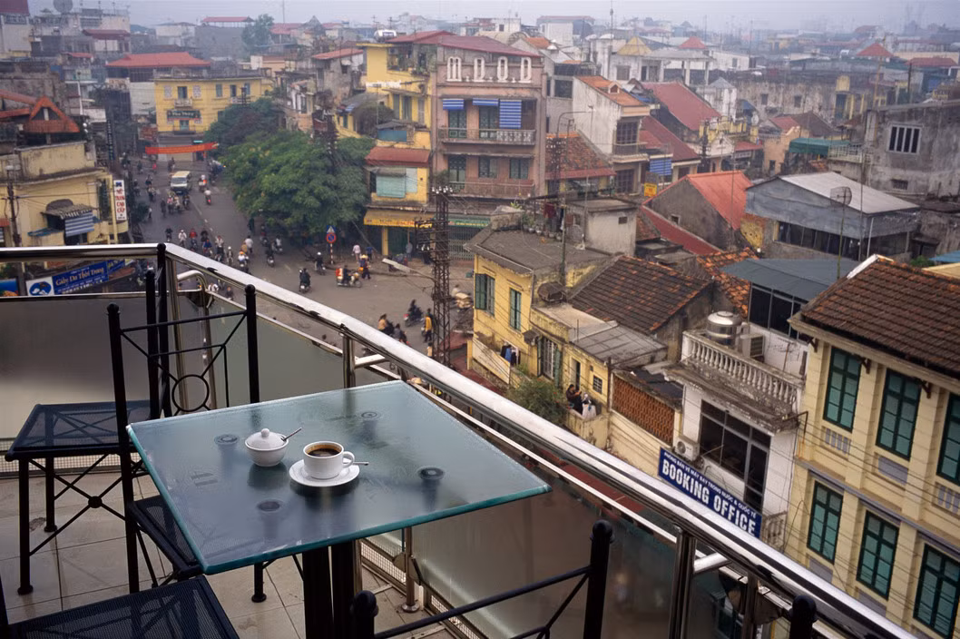 Thưởng thức cà phê trên sân thượng tòa nhà "Hàm cá mập" ở Ngã năm bờ hồ, Hà Nội năm 2004. Ảnh: David Alan Harvey/ Magnum Photos.
