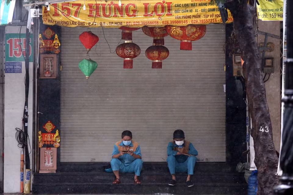 Hai nhân viên viễn thông trú mưa trước của một cửa hàng đang đóng cửa.