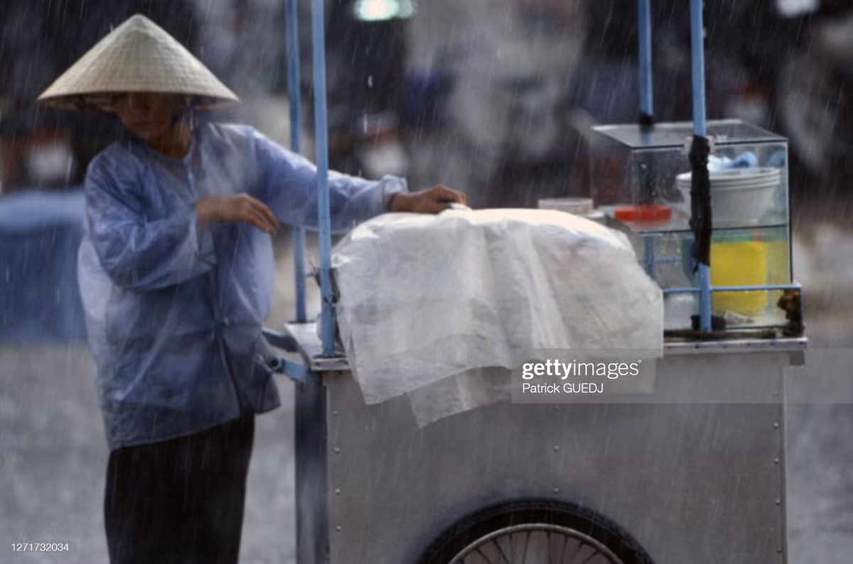 Người bán hàng đẩy xe trên đường phố dưới cơn mưa ở thị xã Vĩnh Long.