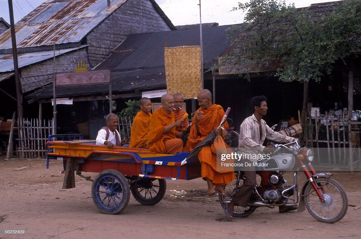 Một nhóm nhà sư di chuyển trên đường phố bằng xe ba gác.